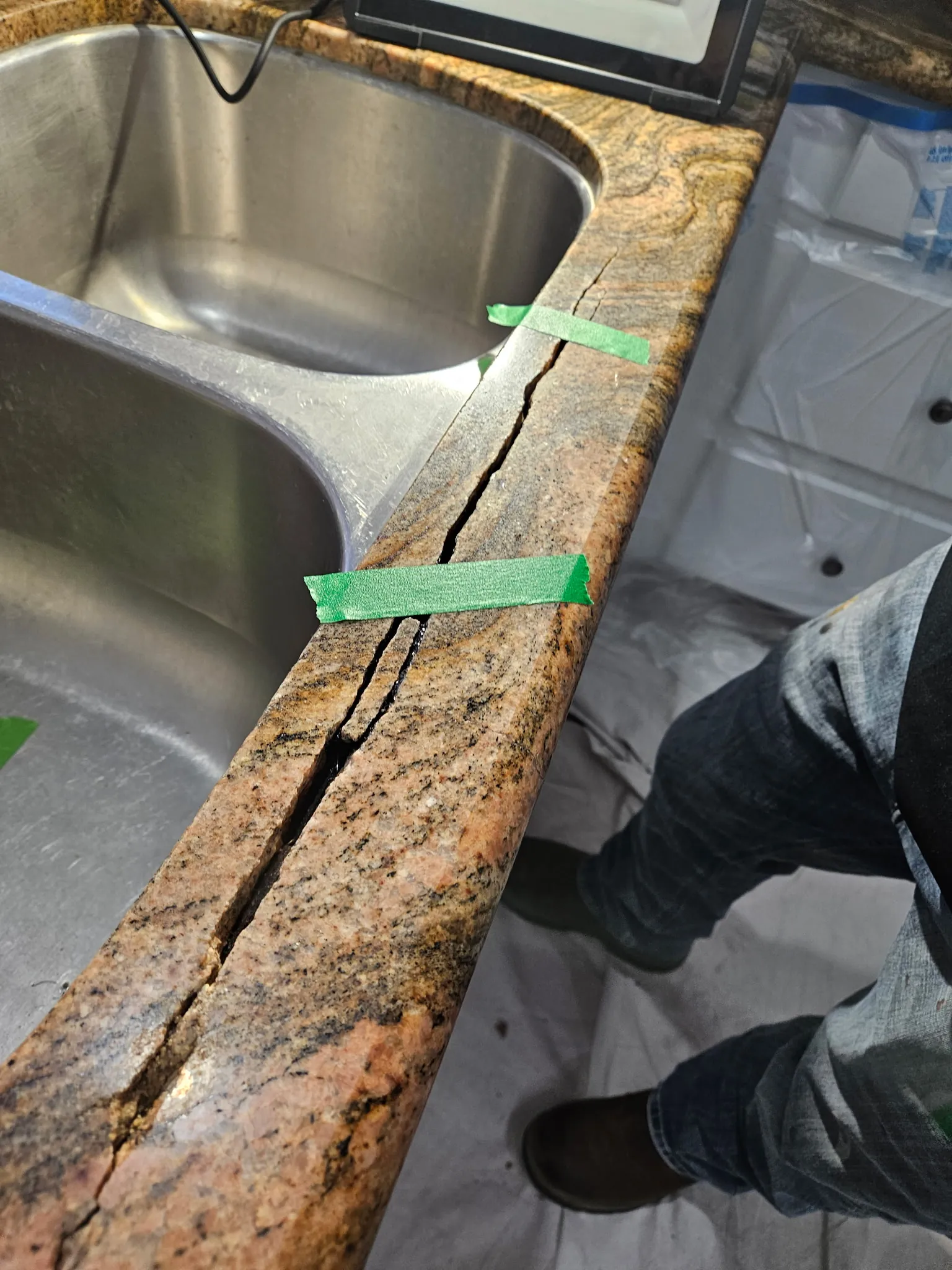 Cracked granite countertop edge held in place with green painter's tape during assessment near Craig Ranch
