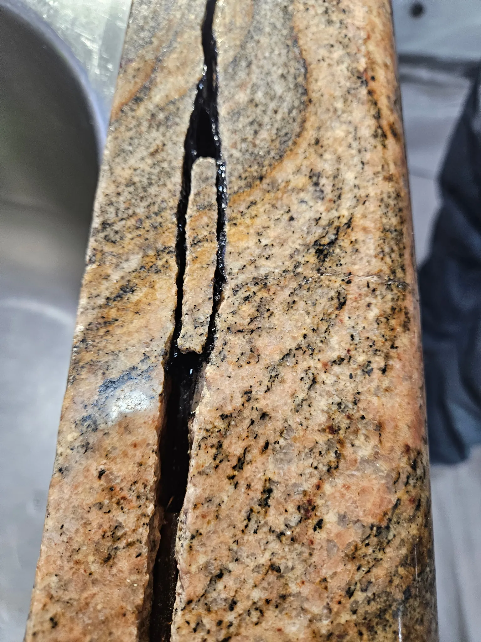 Granite countertop crack filled and sealed with color-matched structural epoxy during restoration