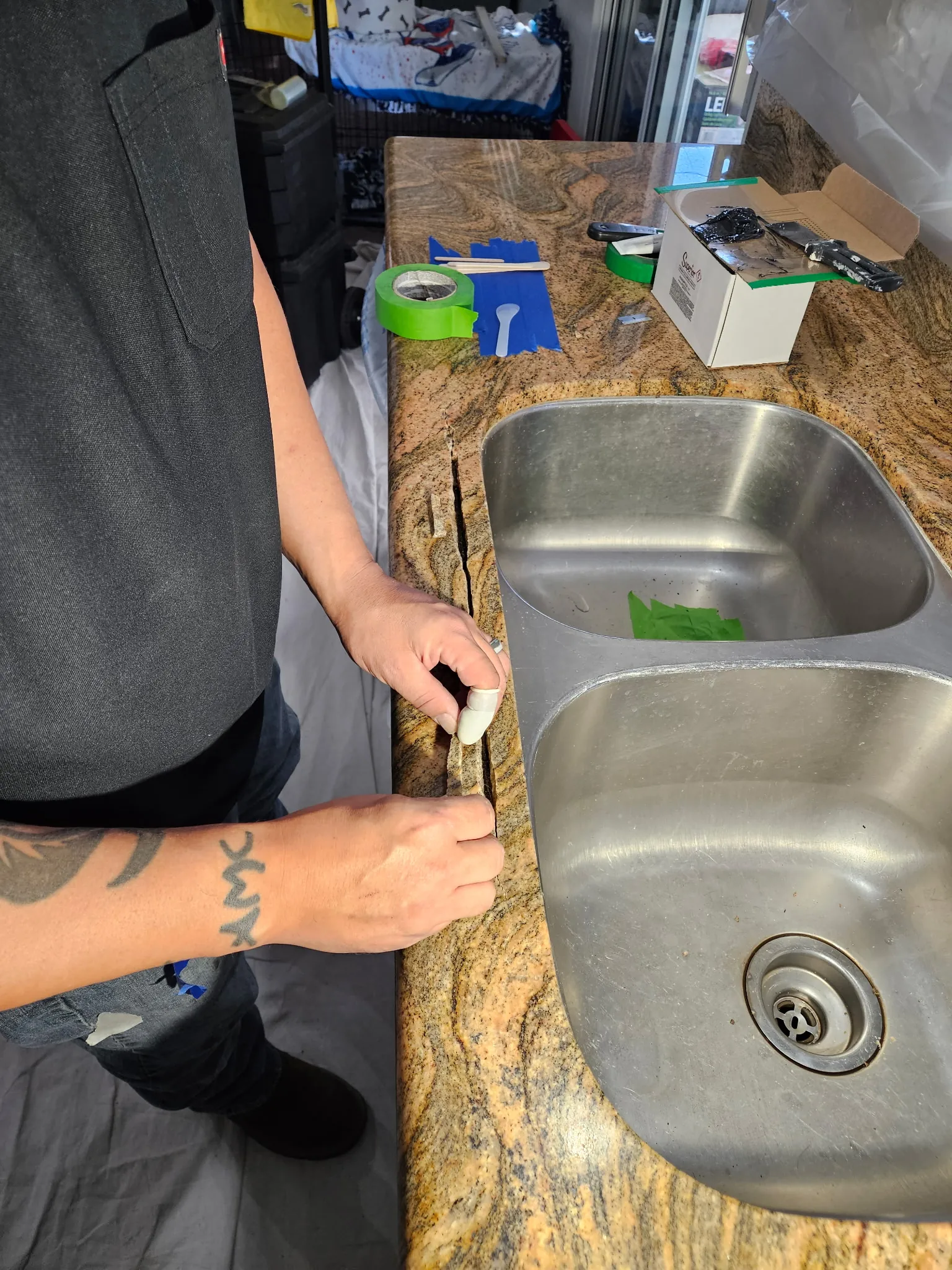 Technician filling granite countertop crack with epoxy
