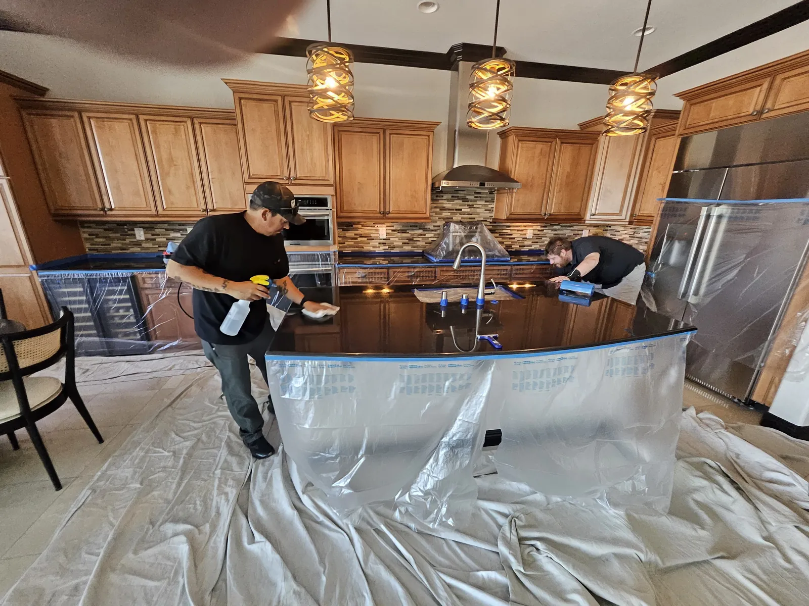 Technicians cleaning and polishing a dark granite kitchen countertop in Henderson