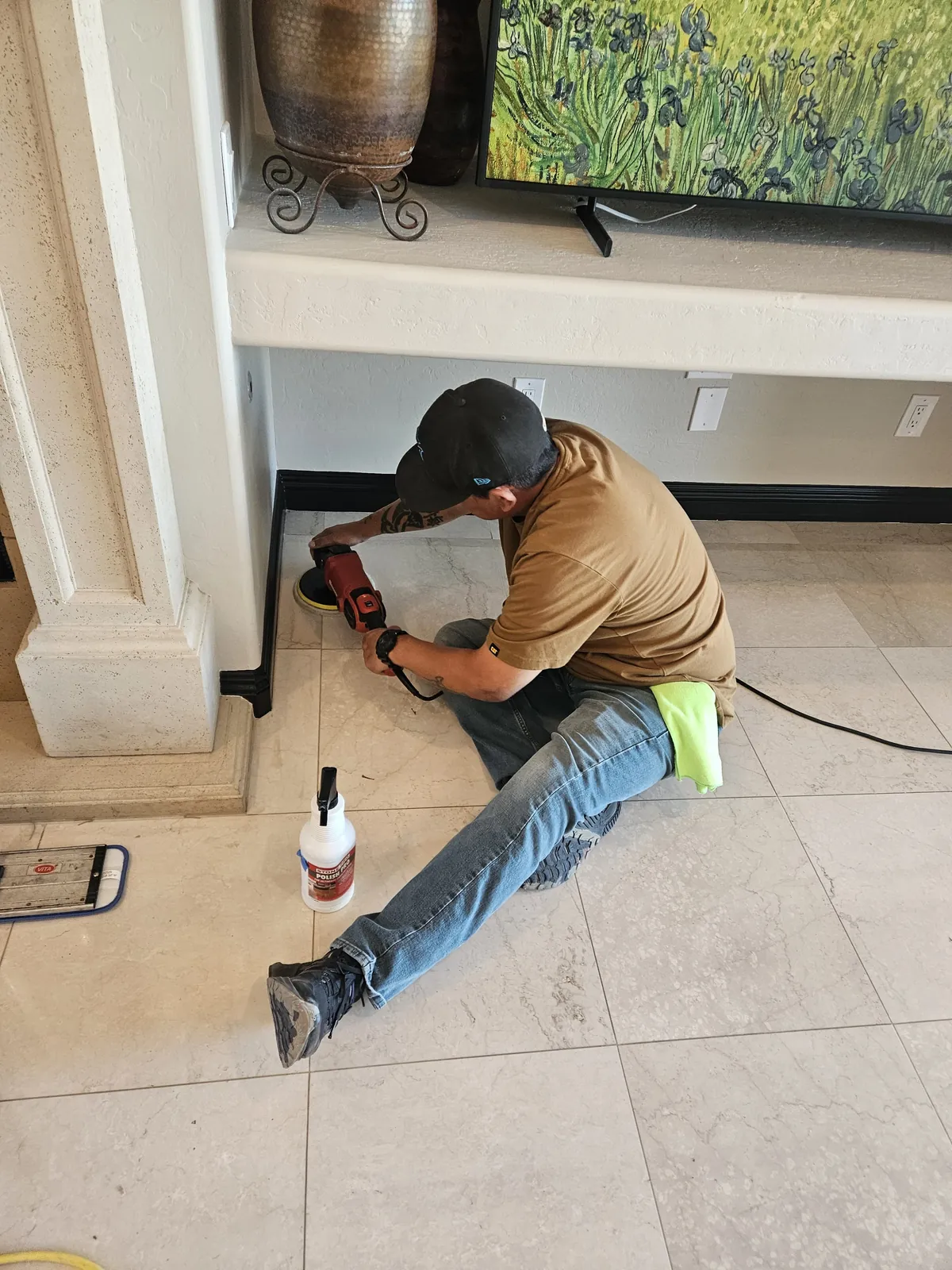 Technician polishing marble floor edges near a fireplace in Henderson Nevada