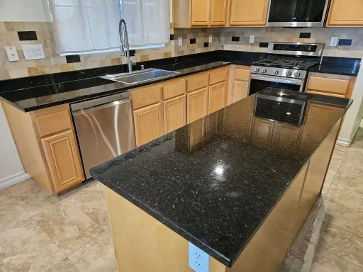 Cracked dark stone kitchen island before repair, and the same island after (after)
