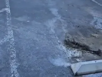 Asphalt parking lot outside the entrance, where grit tracks onto the vinyl plank floor