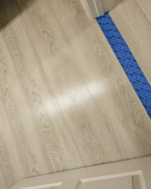 Light oak-look vinyl plank floor at a Las Vegas commercial job, finished, with a taped transition at the doorway