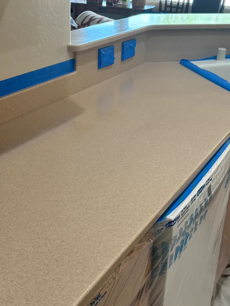 Blue tape and plastic protecting the wall and cabinets around a countertop work area