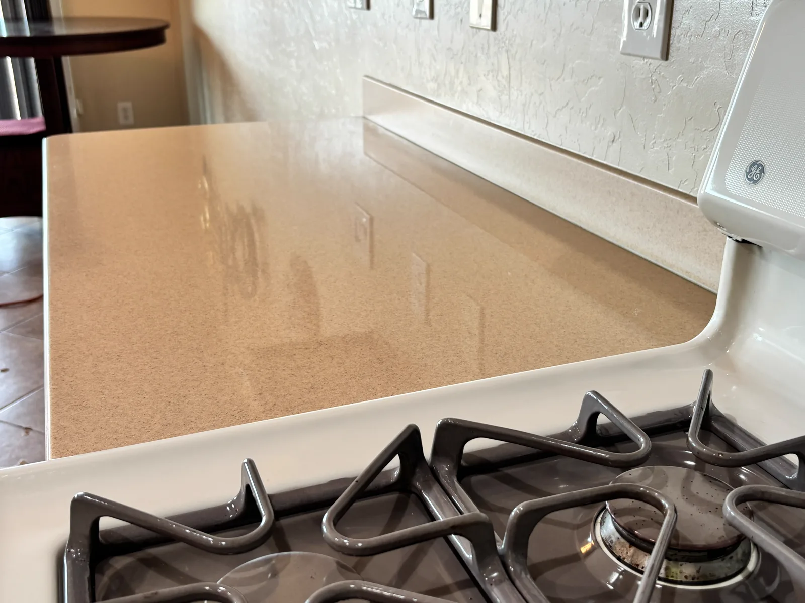 Finished beige countertop beside a white stove with reflections visible across the surface