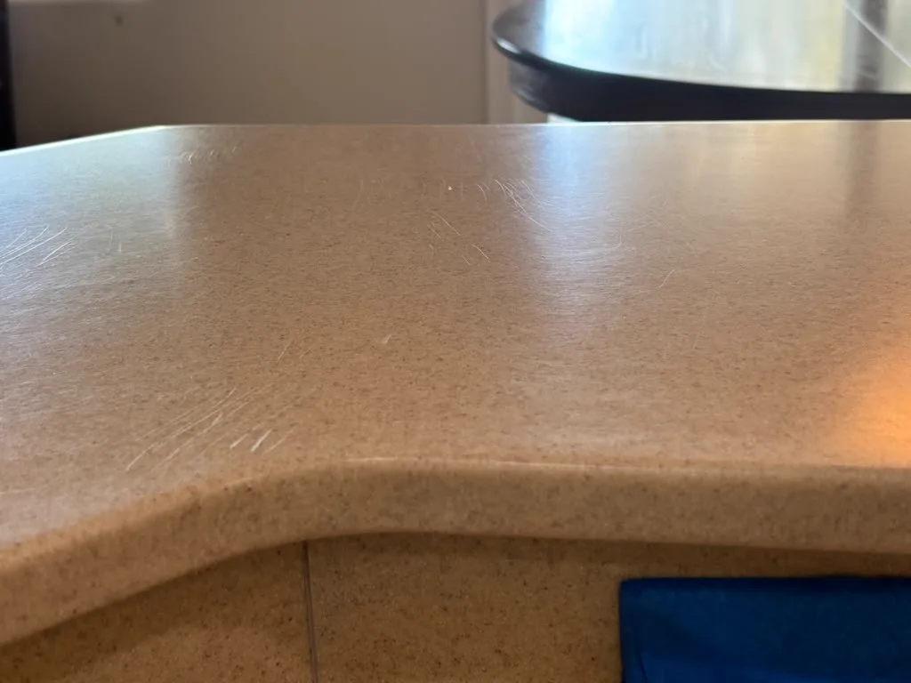 Fine scratches crossing a beige solid-surface countertop before refinishing