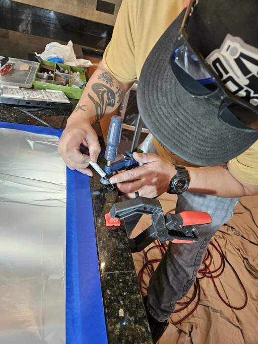 Technician clamping dark granite countertop crack during repair