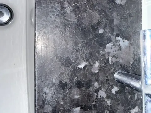 Fine hairline cracks across a dark granite bathroom vanity top