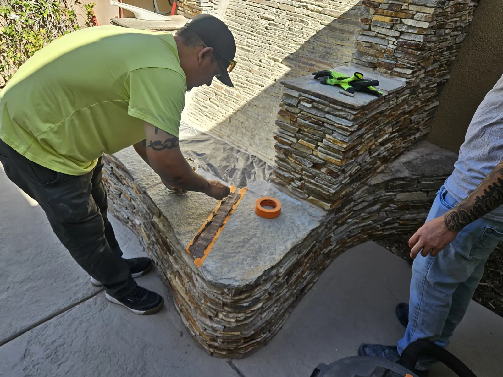 Technician repairing a mortar joint on a stone fountain cap with color-matched fill