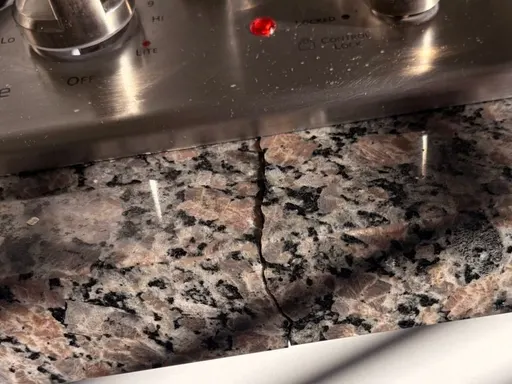 Crack running through a granite countertop in front of a cooktop