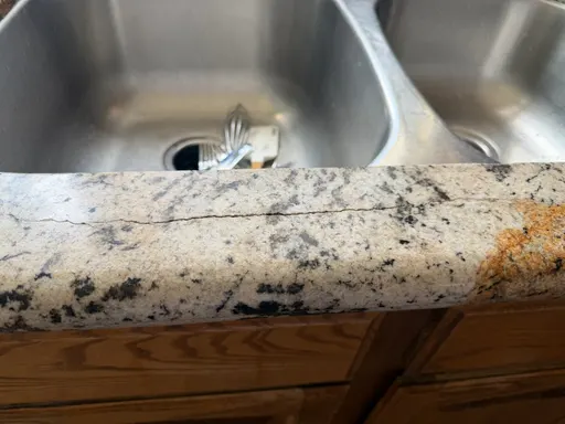 Crack running along the narrow granite strip in front of an undermount sink