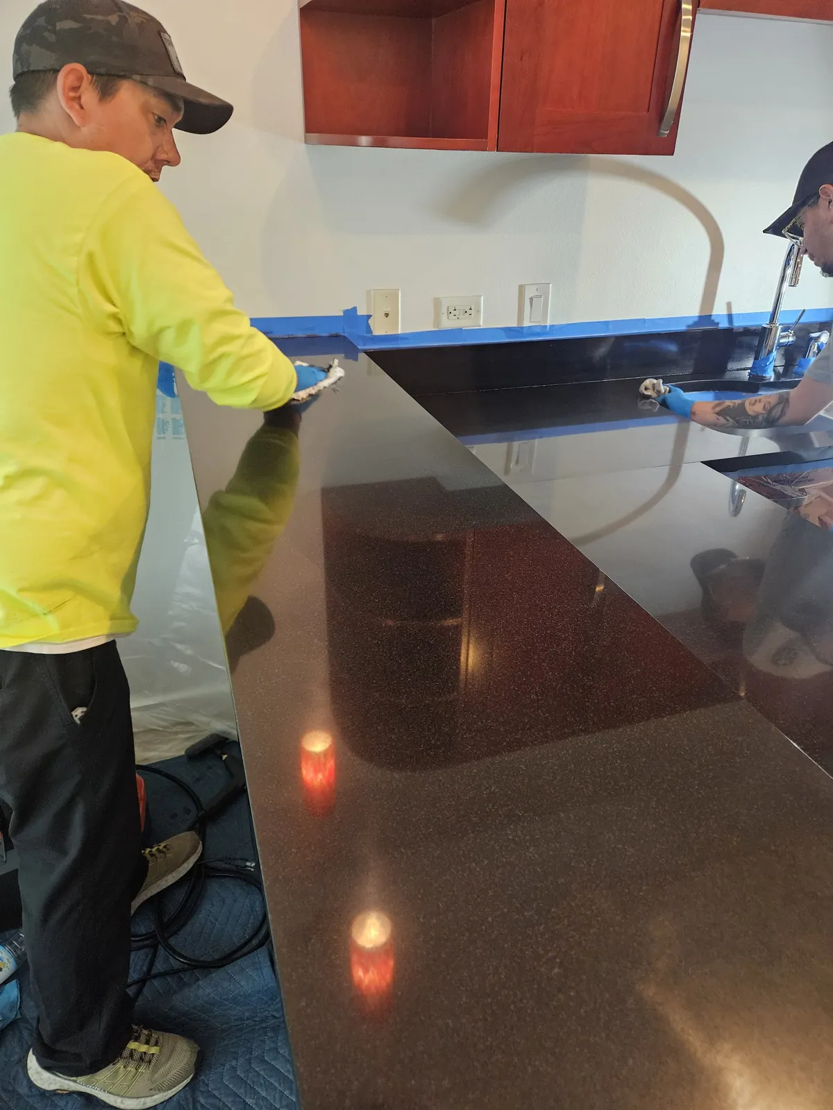 Technician hand-polishing a black granite bar top near Panorama Towers