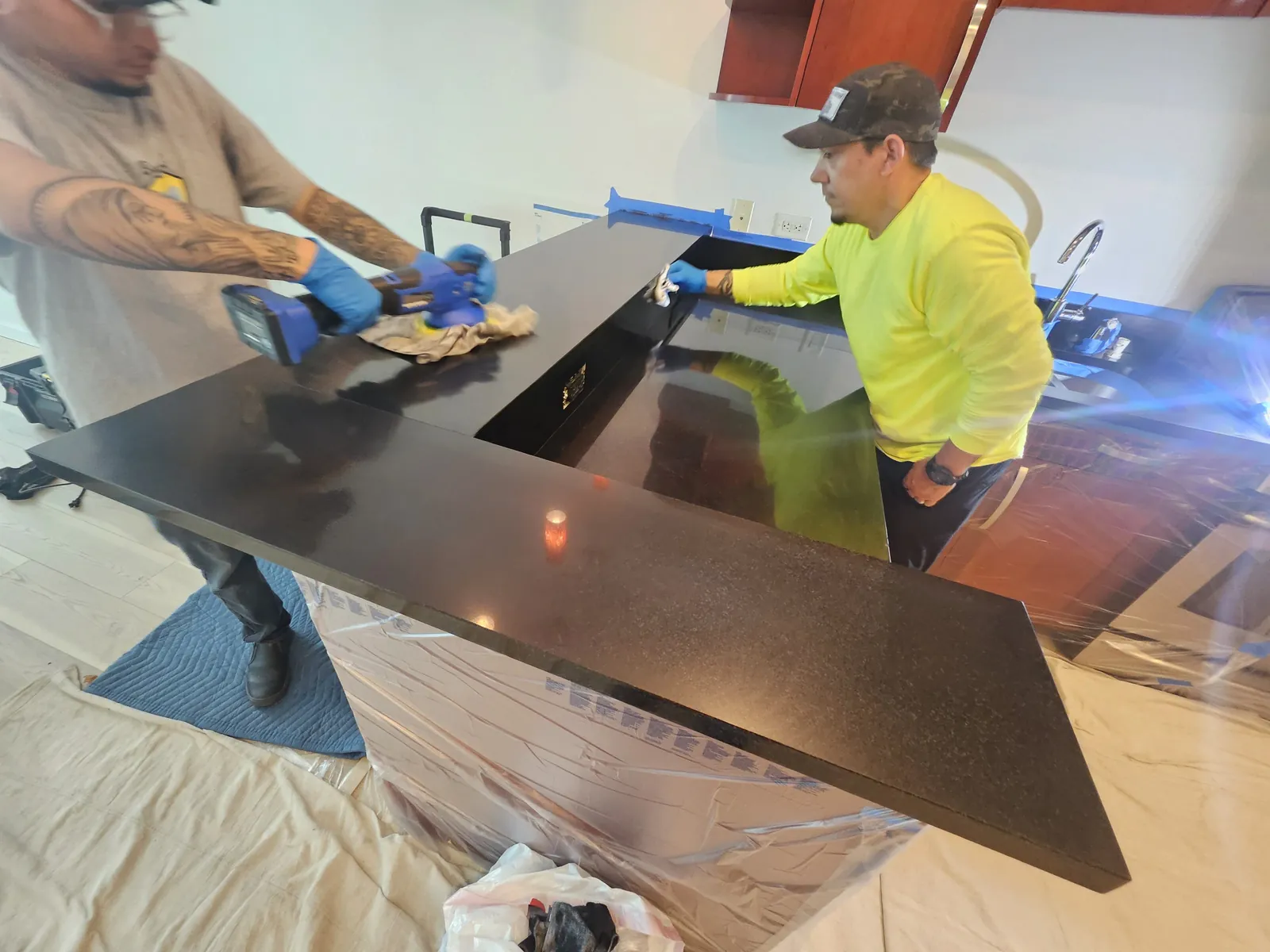 Technicians restoring a black granite countertop near Panorama Towers