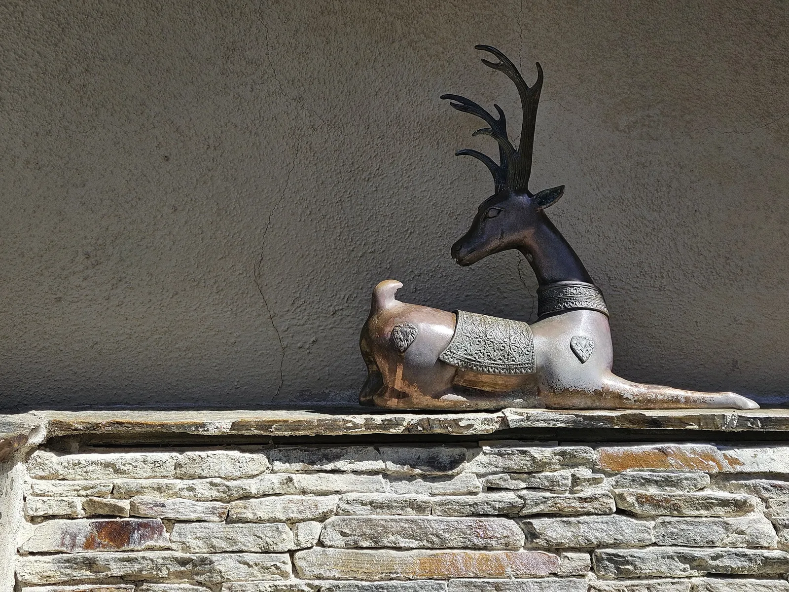 Refinished metal deer statue on a stacked stone water feature