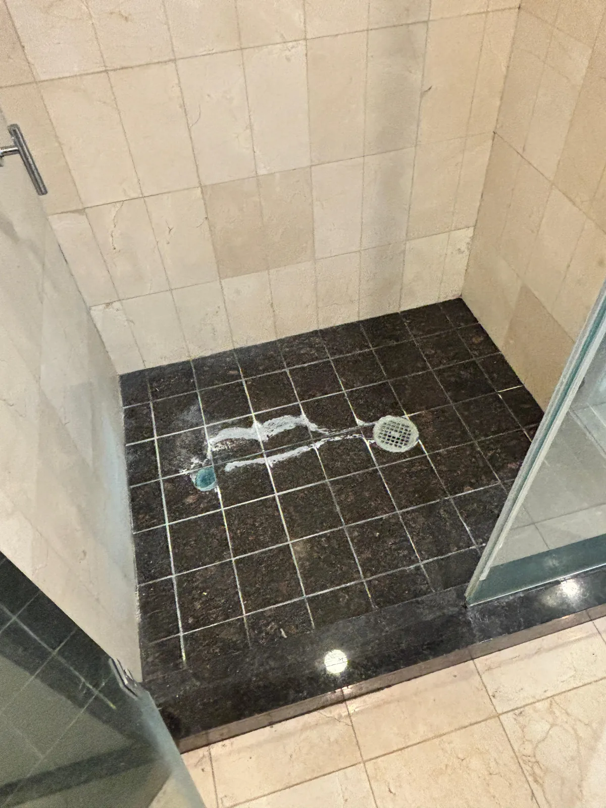 Granite shower floor with hard water buildup before cleaning near Sky Las Vegas