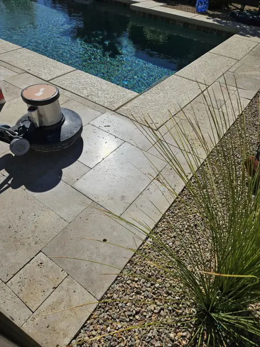 Technician honing travertine pool coping during restoration