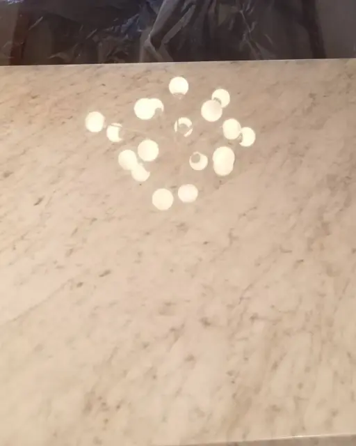 Polished marble countertop reflecting chandelier